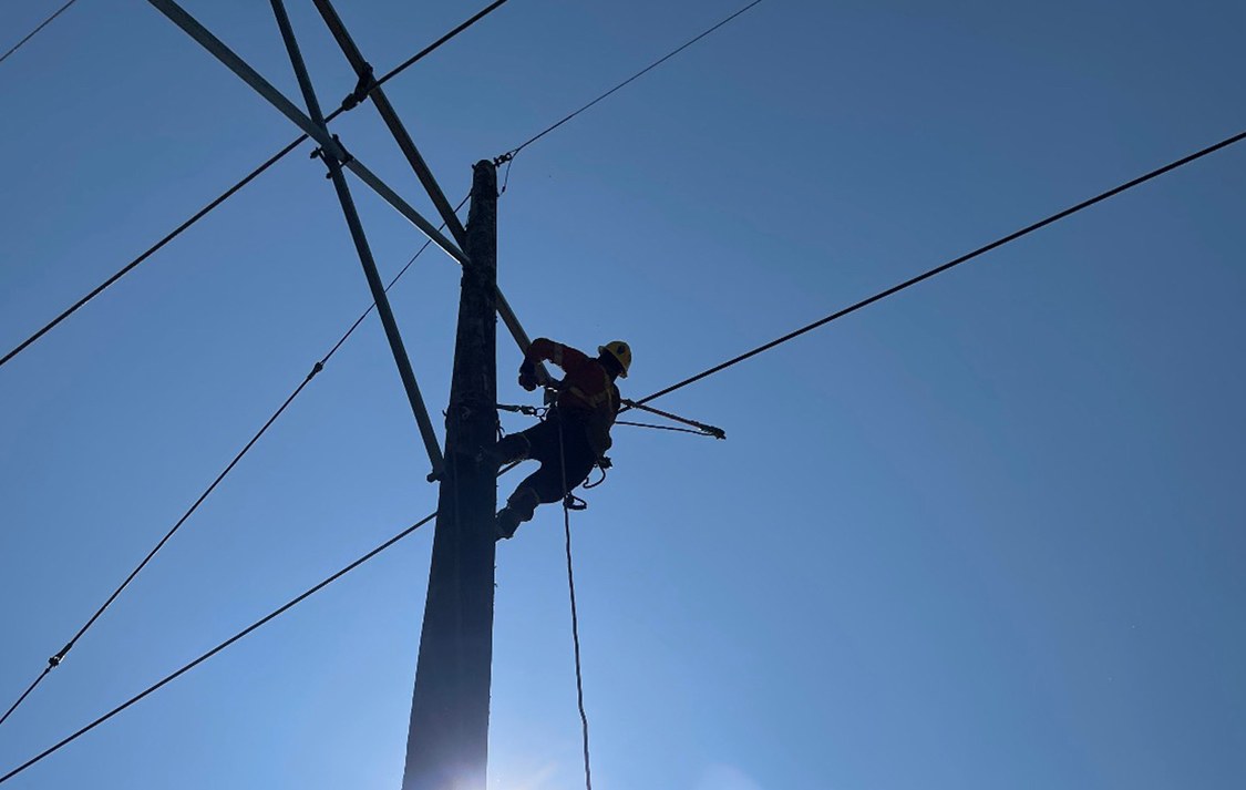 Powerline technician working on utility pole — authentic field photograph highlighting October Issue 02